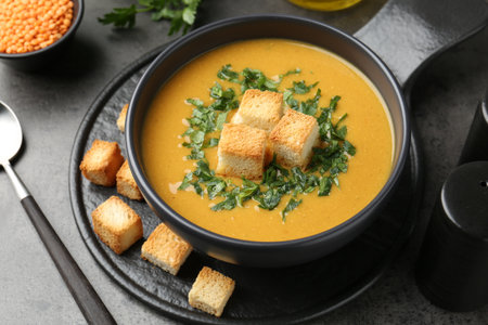 Delicious lentil cream soup served with croutons on gray table, closeupの写真素材