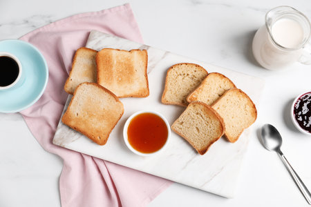 Slices of tasty toasted bread and jam on white marble table, flat layの写真素材