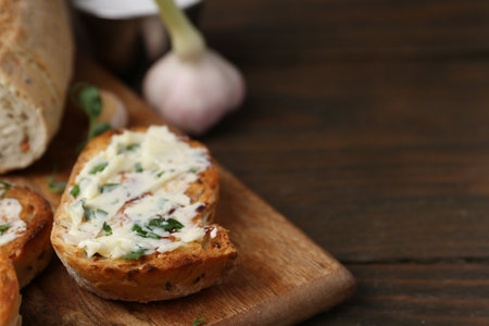 Tasty bread with garlic, herbs and oil on wooden table, closeup. Space for textの写真素材