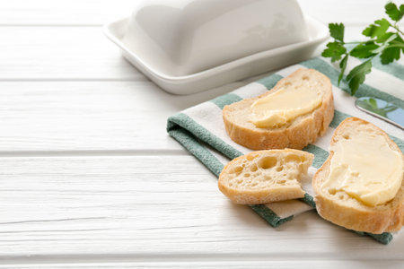 Slices of bread with butter on white wooden table. Space for textの写真素材