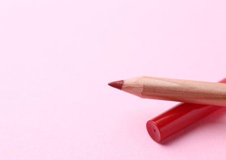 One lip pencil on light pink background, closeup. Space for textの写真素材
