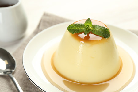 Delicious pudding with caramel sauce and mint served on white table, closeupの写真素材