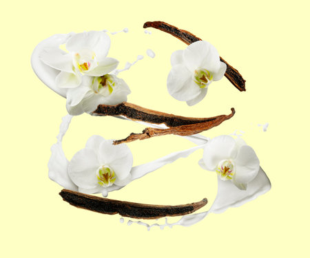 Vanilla milk splash, flowers and pods in air on pale yellow background