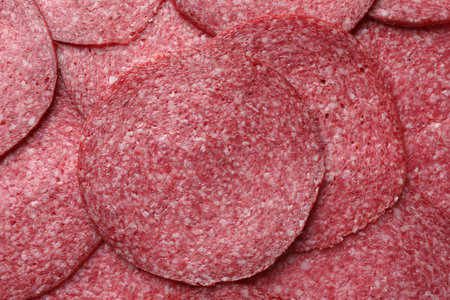Slices of tasty smoked sausage as background, top view