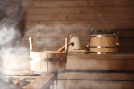 Bucket, ladle and other bath supplies surrounded by steam in saunaの写真素材