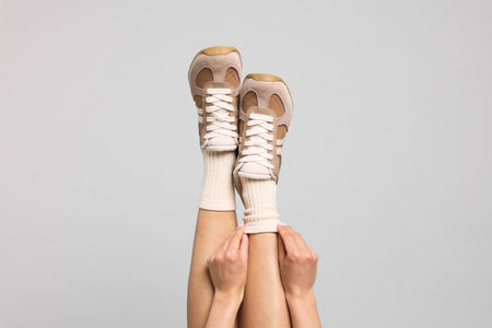Woman in stylish beige socks and sneakers on light grey background, closeupの写真素材
