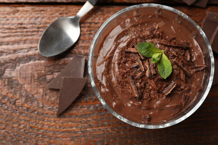 Tasty pudding with mint and pieces of chocolate served on wooden table, flat layの写真素材