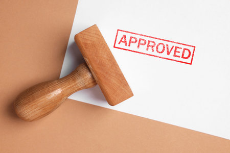 Sheet of paper with word Approved and stamp on beige background, top viewの写真素材