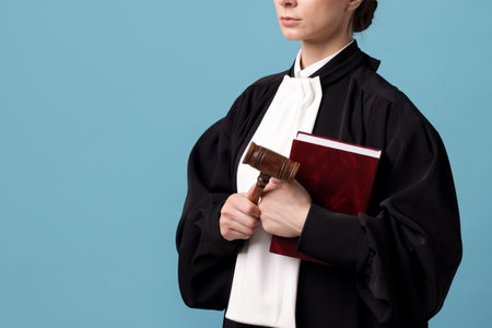 Judge with mallet and book on light blue background, closeup. Space for textの写真素材