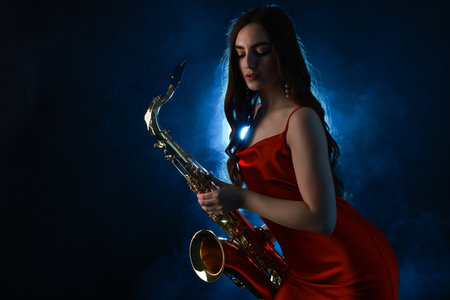 Professional musician playing saxophone on dark background with blue light and smokeの写真素材