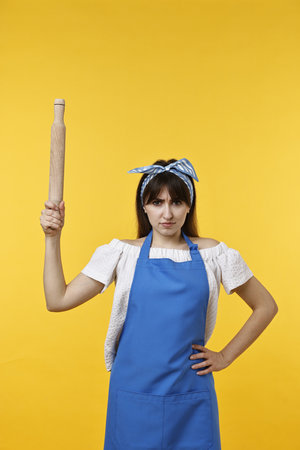Woman with rolling pin on yellow backgroundの写真素材