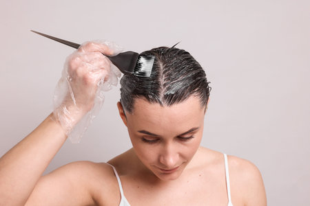 Beautiful woman dyeing her hair on gray backgroundの写真素材