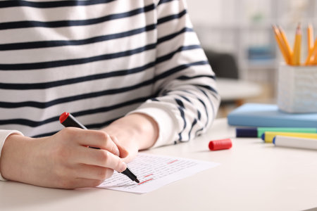 Woman circling important information with marker at white desk indoors, closeup