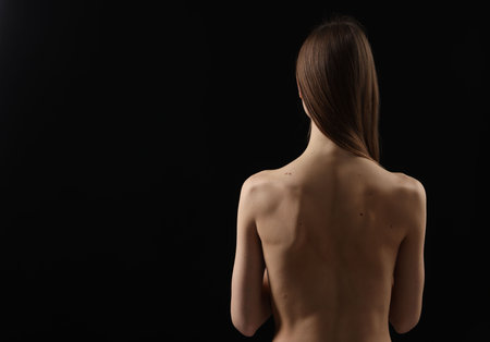 Woman on black background, back view. Space for textの写真素材