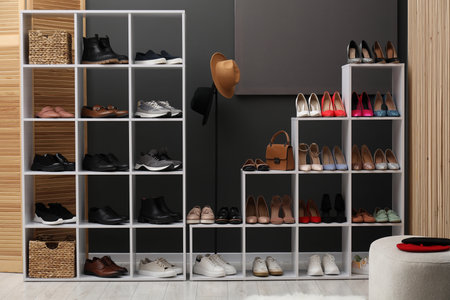 Shoe storage. Shelving unit with different footwear and accessories near grey wall indoorsの写真素材
