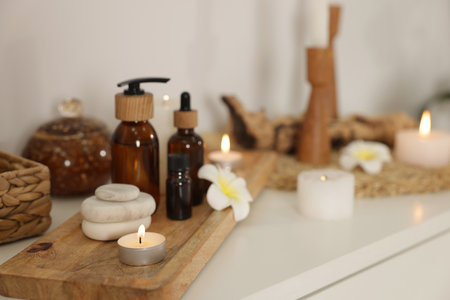 Spa stones, cosmetic products, burning candles and orchid flowers on white table indoorsの写真素材