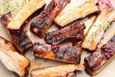 Delicious pork ribs and thyme on parchment paper, top view
