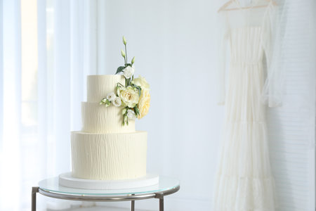 Delicious wedding cake with floral decor on table indoors, space for textの写真素材