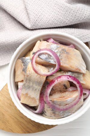 Pieces of delicious herring with onions on white table, top viewの写真素材