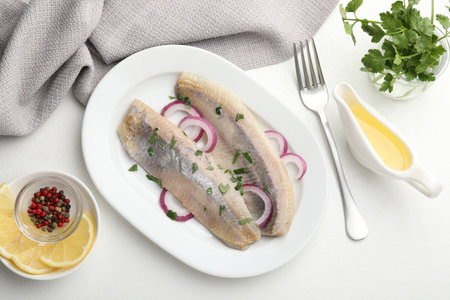 Tasty herring fillets with onions and parsley served on white table, flat layの写真素材
