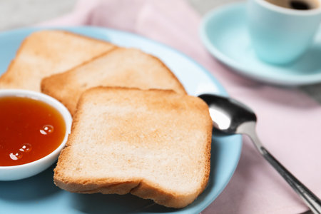 Slices of tasty toasted bread, jam and spoon on pink tablecloth, closeupの写真素材