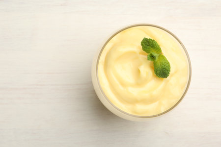 Tasty vanilla pudding with mint on white wooden table, top view. Space for textの写真素材
