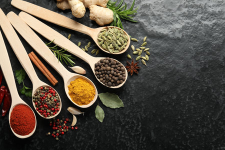 Many different spices in spoons on black table, flat lay. Space for textの写真素材