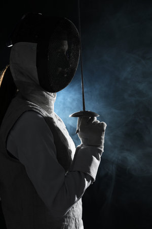 Fencer with epee in smoke on black background