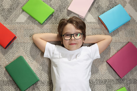 Boy with many different books on floor at home, top viewの写真素材
