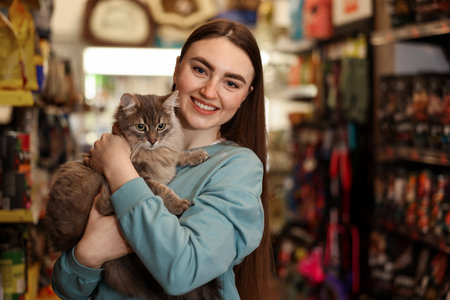 Happy woman with her cute cat in pet shop. Space for textの写真素材