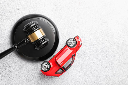 Motor vehicle accident law. Gavel and car model on gray background. Space for textの写真素材
