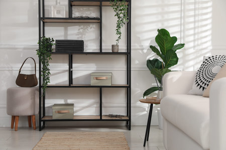 Stylish shelving unit with decor near white wall indoorsの写真素材