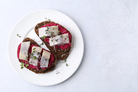 Tasty sandwiches with herring and horseradish sauce on light table, top view. Space for text