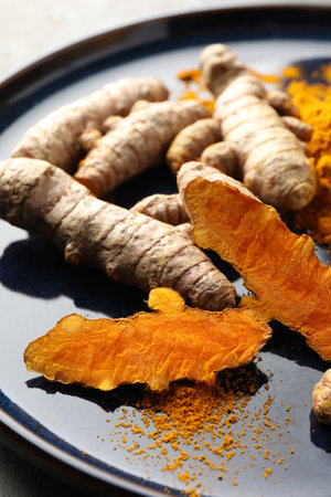 Aromatic turmeric powder and fresh roots on table, closeupの写真素材