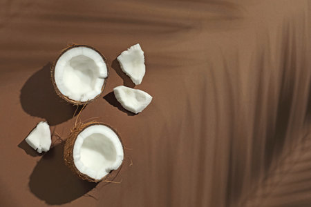 Fresh coconut and shadow cast by tropical palm on beige background, flat lay. Space for text