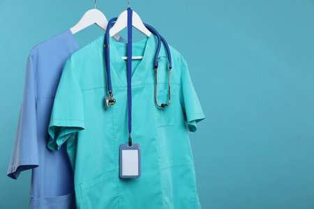 Medical workers uniforms with stethoscope and badge on hangers against blue background. Space for textの写真素材