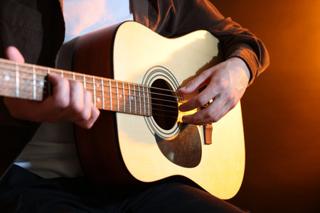Man playing guitar on brown background, closeup