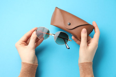 Woman with sunglasses and case on light blue background, top viewの写真素材