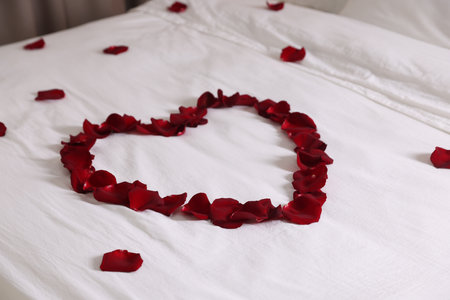 Heart made with beautiful rose petals on bedの写真素材