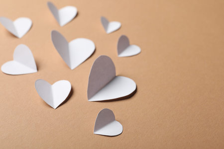 Many paper hearts on beige background, closeup. Space for text