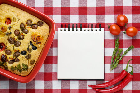 Blank recipe book, focaccia and ingredients on checkered tablecloth, top view. Mockup for design