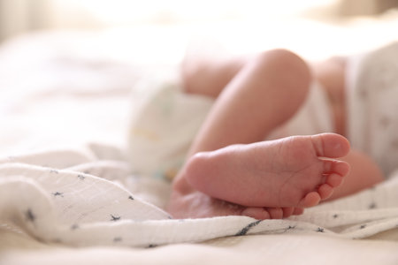 Little baby lying on bed indoors, closeup. Space for textの写真素材