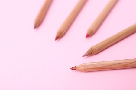 Many different lip pencils on light pink background, closeup. Space for textの写真素材