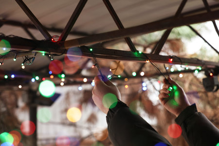 Man decorating house with Christmas lights outdoors, closeup