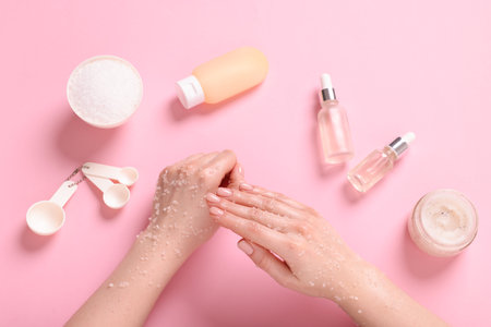 Woman applying body scrub onto her hand on pink background, top viewの写真素材