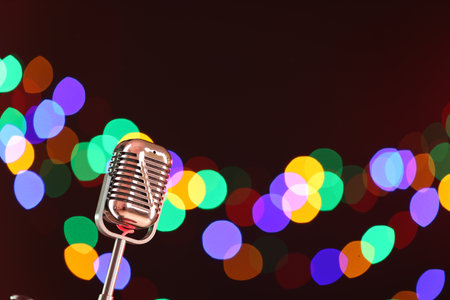 Vintage microphone on dark background with blurred lights, space for text. Musical equipmentの写真素材