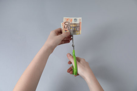 Woman cutting euro banknote on gray background, top viewの写真素材