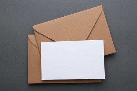 Blank greeting card and envelopes on gray background, top view