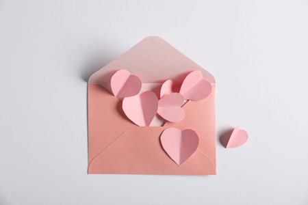 Many paper hearts and envelope on light grey background, flat lay