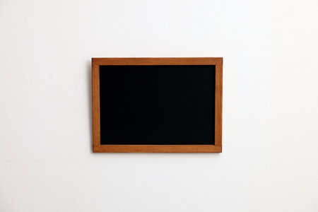 One small blank blackboard on white wallの写真素材